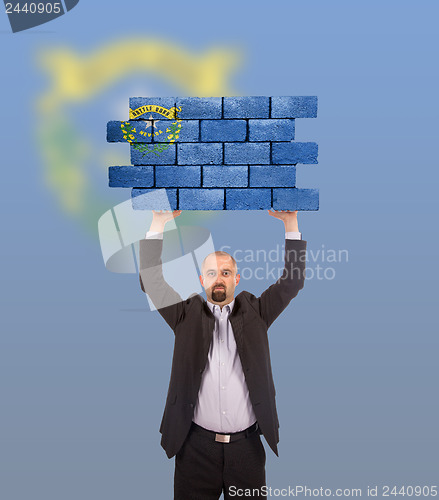 Image of Businessman holding a large piece of a brick wall