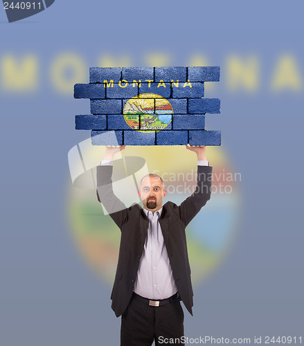 Image of Businessman holding a large piece of a brick wall