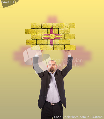 Image of Businessman holding a large piece of a brick wall