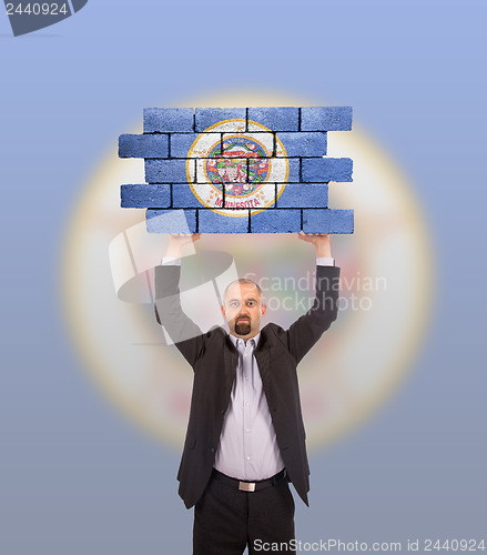 Image of Businessman holding a large piece of a brick wall