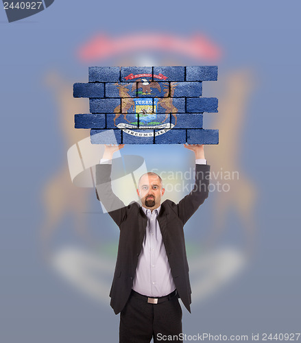 Image of Businessman holding a large piece of a brick wall