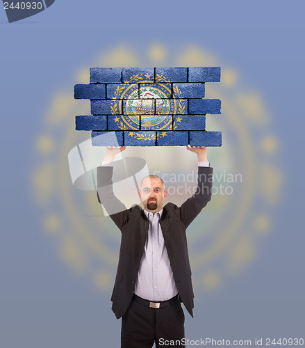 Image of Businessman holding a large piece of a brick wall