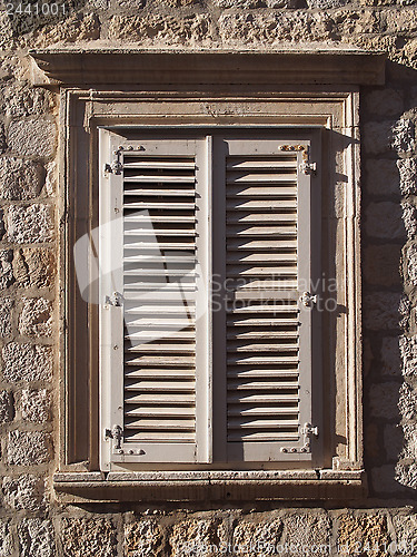 Image of mediterranean stone window with wood shutters