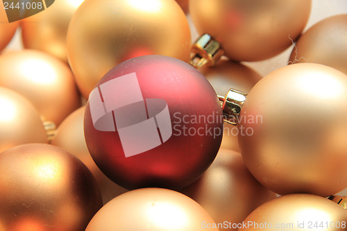 Image of Red ornament on a pile of golden ornaments