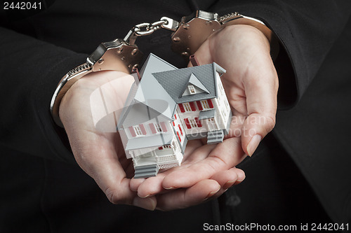 Image of Woman In Handcuffs Holding Small House