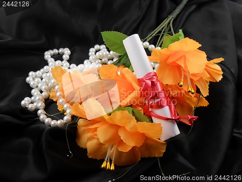 Image of orange flowers, white paper and white diamonds on black background