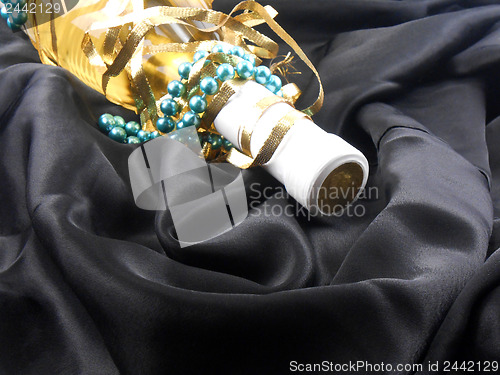Image of bottle of champagne wine with blue diamonds on black material background