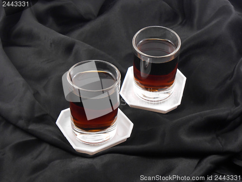 Image of two glasses with red wine on black material background