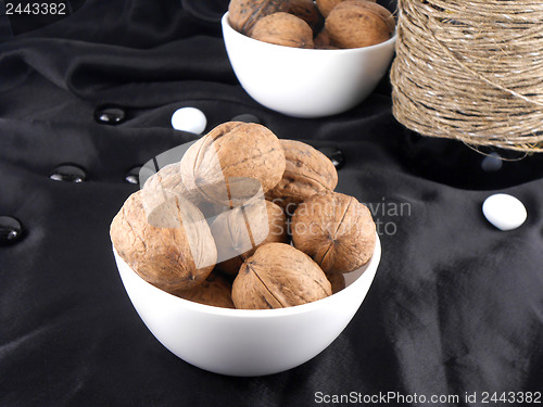 Image of bottle and walnuts on black material with stones