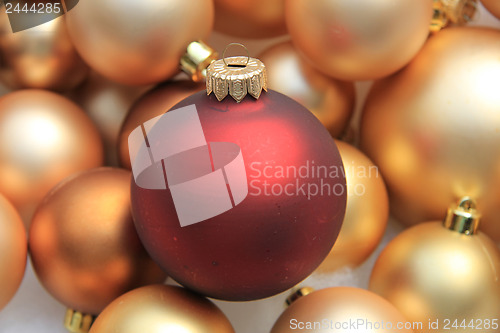 Image of Red ornament on a pile of golden ornaments