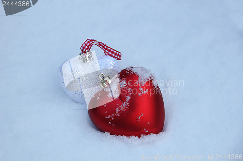 Image of Red and white heart ornaments in snow