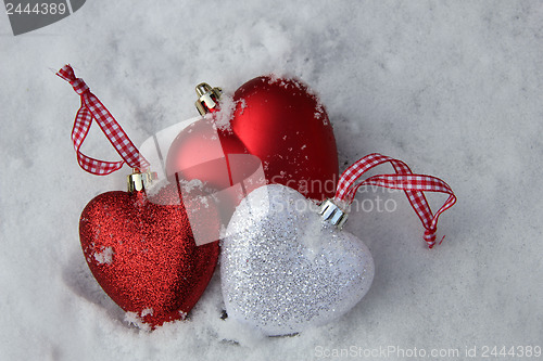 Image of Red and white heart ornaments in snow