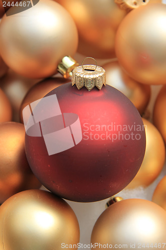 Image of Red ornament on a pile of golden ornaments