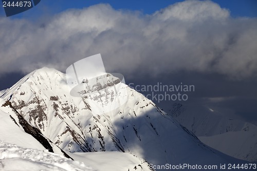 Image of Snowy sunlit mountains and blue sky with clouds