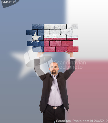 Image of Businessman holding a large piece of a brick wall