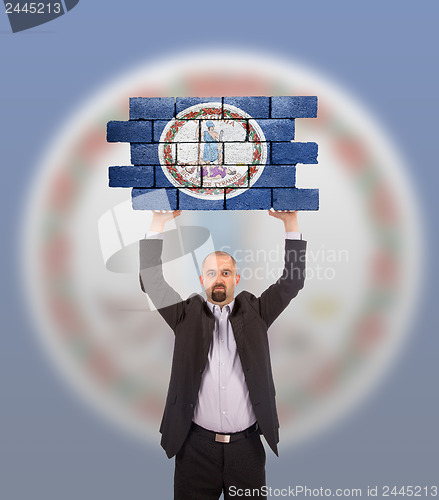 Image of Businessman holding a large piece of a brick wall