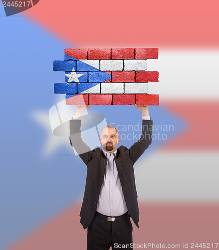 Image of Businessman holding a large piece of a brick wall