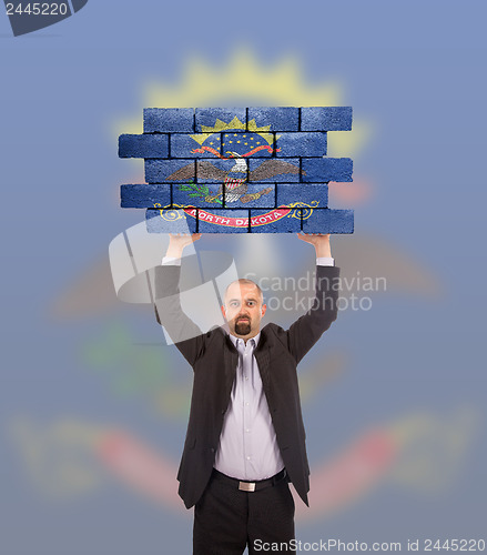 Image of Businessman holding a large piece of a brick wall