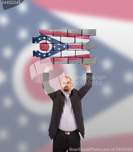 Image of Businessman holding a large piece of a brick wall