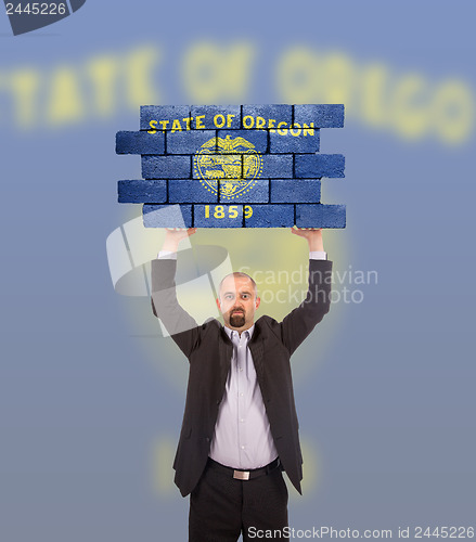 Image of Businessman holding a large piece of a brick wall