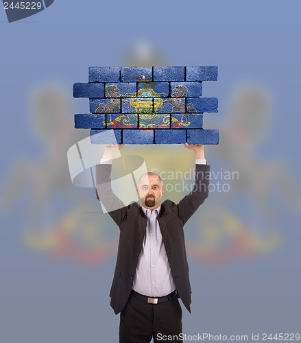 Image of Businessman holding a large piece of a brick wall