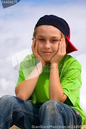 Image of Smiling boy relaxing head in hands
