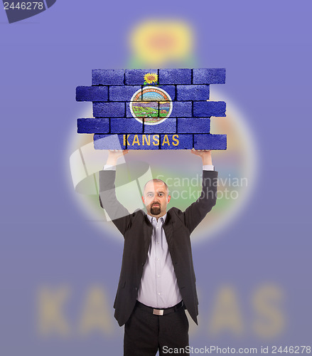 Image of Businessman holding a large piece of a brick wall