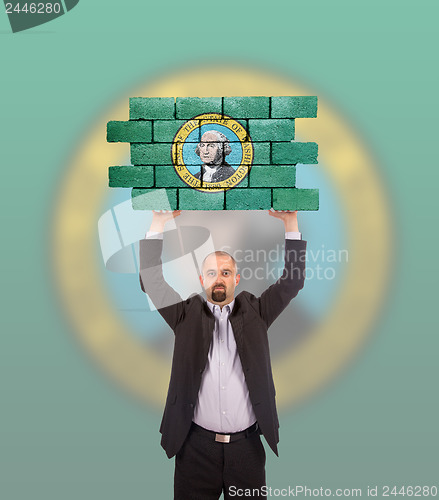 Image of Businessman holding a large piece of a brick wall