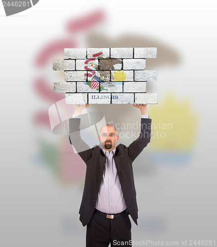 Image of Businessman holding a large piece of a brick wall