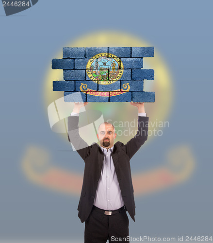 Image of Businessman holding a large piece of a brick wall