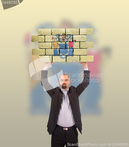 Image of Businessman holding a large piece of a brick wall