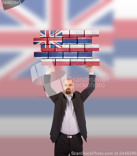 Image of Businessman holding a large piece of a brick wall