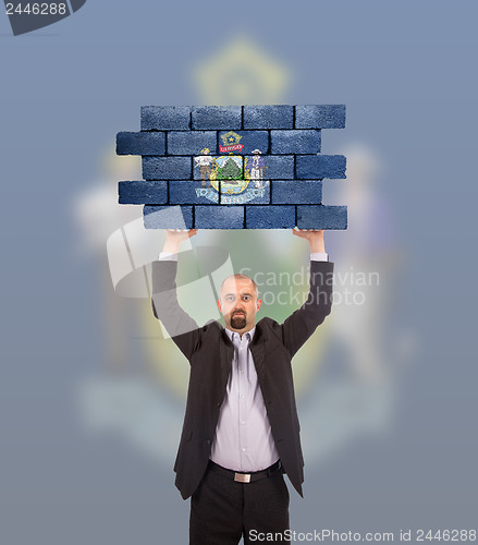 Image of Businessman holding a large piece of a brick wall