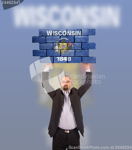 Image of Businessman holding a large piece of a brick wall
