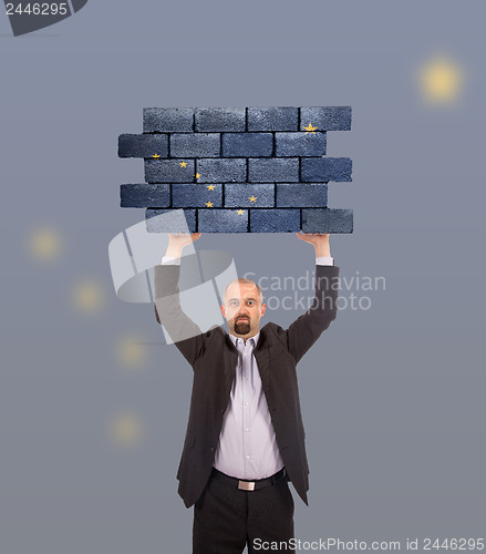 Image of Businessman holding a large piece of a brick wall