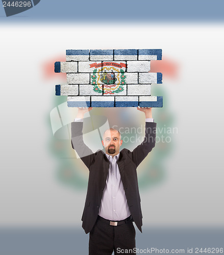 Image of Businessman holding a large piece of a brick wall