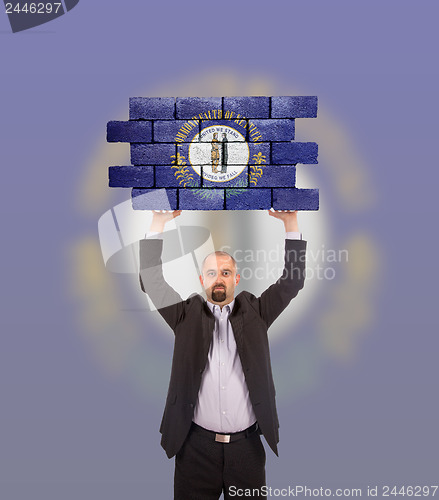 Image of Businessman holding a large piece of a brick wall