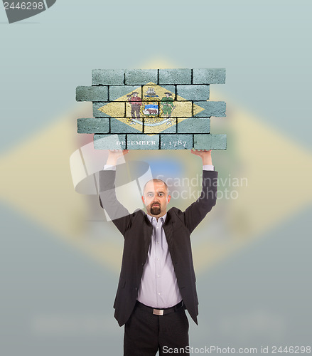 Image of Businessman holding a large piece of a brick wall