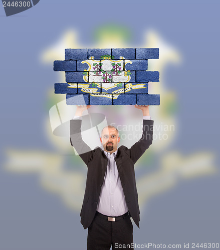 Image of Businessman holding a large piece of a brick wall