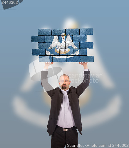 Image of Businessman holding a large piece of a brick wall