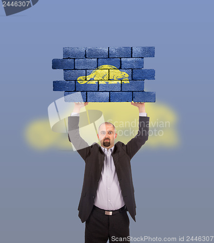 Image of Businessman holding a large piece of a brick wall