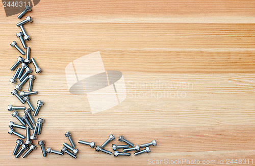 Image of Socket head screws as L-shape border on woodgrain background
