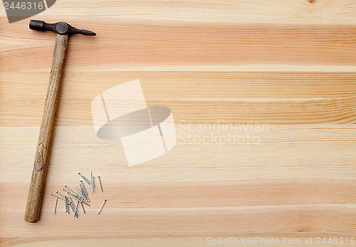 Image of Hammer and metal panel pins on a woodgrain background