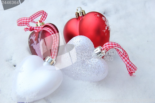 Image of Red and white heart ornaments in snow