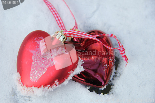 Image of Red and white heart ornaments in snow