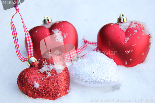 Image of Red and white heart ornaments in snow