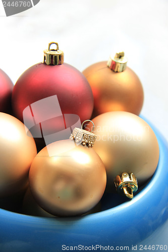 Image of red and golden christmas ornaments in a blue bowl