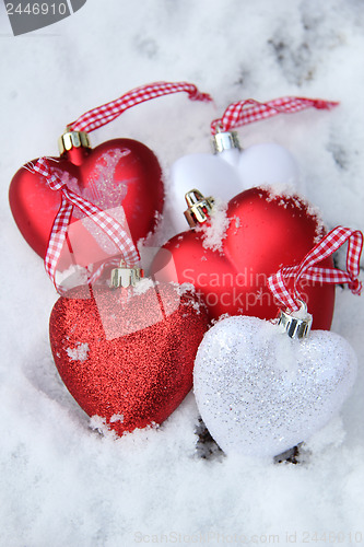 Image of Red and white heart ornaments in snow