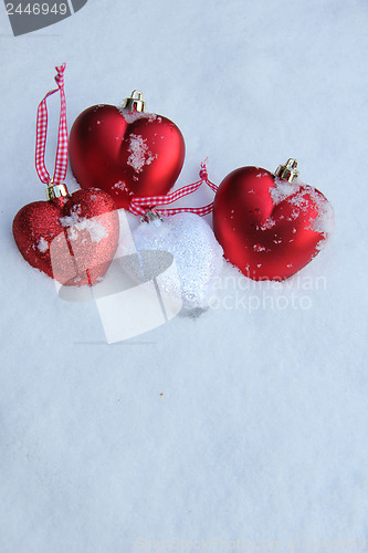 Image of Red and white heart ornaments in snow