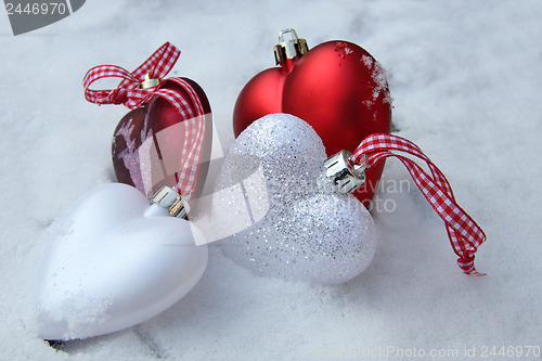 Image of Red and white heart ornaments in snow